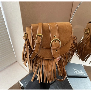 Detail of vintage brown suede saddle bag featuring long fringes and metal buckle detail