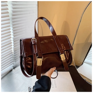 Detailed view of deep brown glossy vintage messenger bag with gold buckles