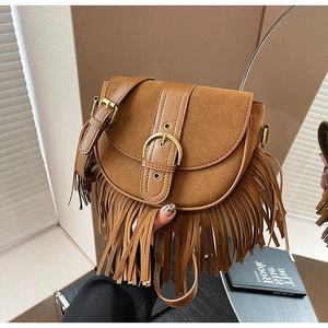 Detail view of brown suede saddle bag featuring long fringe tassels and golden buckle