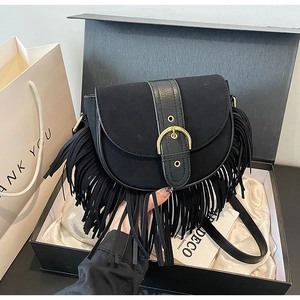 Detail of vintage black tassel crossbody bag with matte texture in a premium gift box