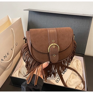 Detailed view of a brown suede tassel saddle bag presented in an elegant gift box