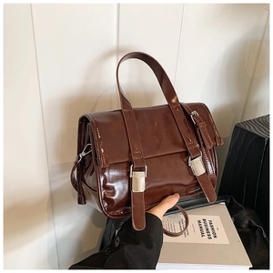 Detail of a vintage dark brown high-shine leather bag with silver metal buckles