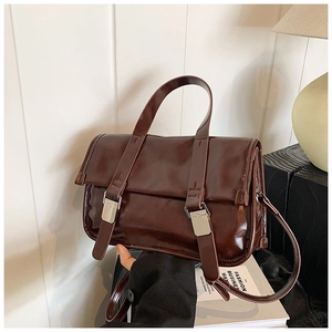 Detail of vintage dark brown faux leather satchel with silver buckle and glossy finish