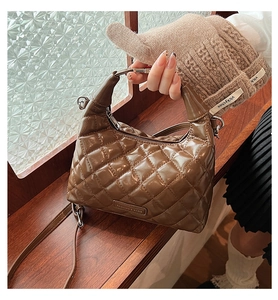 Detail of a brown quilted leather underarm bag with glossy finish and fashion logo