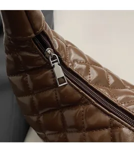 Close-up of smooth silver zipper and quilted diamond pattern on brown leather bag