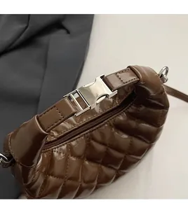 Close-up of premium silver metal buckle and quilted leather texture on brown handbag