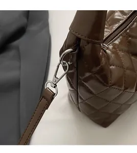 Detailed close-up of the silver metal hook and detachable strap on the brown quilted bag