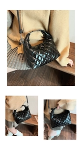 Macro detail of glossy quilted stitching and silver logo on black crossbody handbag