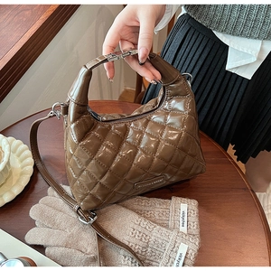 Detailed shot of brown quilted patent leather handbag with retro metal buckle and strap