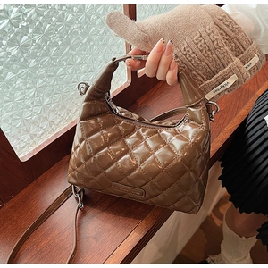 Close-up of brown quilted leather handbag with glossy finish and zipper detail
