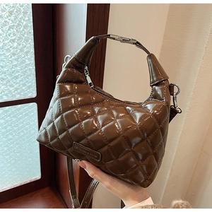 Detail of a brown quilted leather handbag with shiny finish and adjustable strap