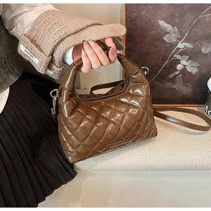 Detail of brown quilted hobo bag with glossy finish and adjustable shoulder strap
