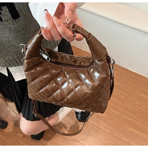 Close-up of brown quilted patent leather handbag with silver zipper and polished finish