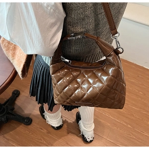 Close-up of brown quilted leather underarm bag featuring silver hardware and a metal logo