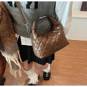 Close-up of quilted dark brown patent leather hobo bag with silver metal hardware detail