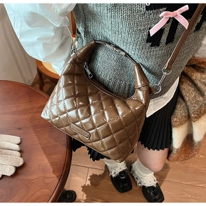 Detail view of brown quilted bag with silver metal handle on a wooden table