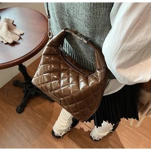 Close-up of brown quilted hobo bag with glossy finish and metal chain handle detail
