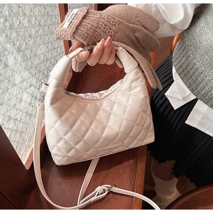 Close-up of quilted ivory hobo bag with glossy PU leather and metal fashion logo detail