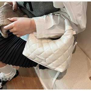 Detail of white quilted patent leather bag with gold logo plate and stylish thin strap
