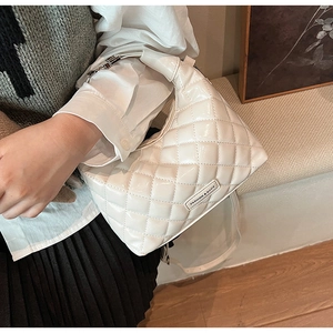 Detail of white quilted leather hobo bag featuring metal fashion brand plaque
