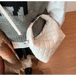 Detail of white quilted crossbody bag with glossy finish and detachable shoulder strap