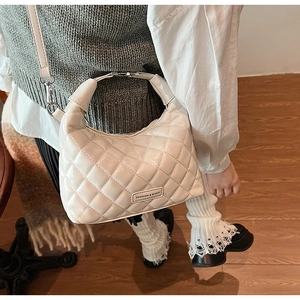 Detail of cream quilted crossbody bag with silver metal handle and fashion logo plate