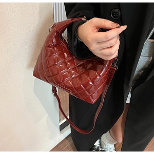 Detailed close-up of wine red quilted faux leather handbag with adjustable strap