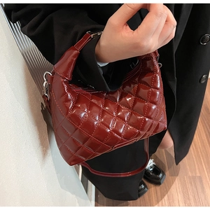 Detail of red quilted patent leather handbag with glossy finish and secure zipper