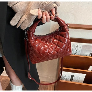 Detailed close-up of red patent leather handbag with quilted stitching and logo