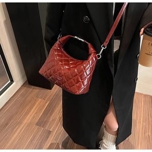Detail view of burgundy quilted patent leather handbag with silver metallic buckle clasp