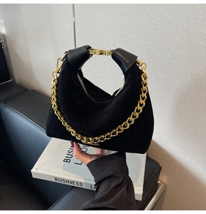 Détail du sac croissant en daim noir avec une chaîne en métal doré texturé élégant