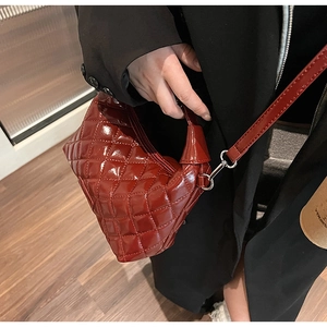 Close-up of glossy quilted rhombus leather texture and silver buckle on shoulder bag
