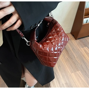 Detail of burgundy patent leather shoulder bag with quilted diamond pattern and glossy finish