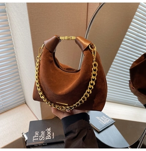 Détail du sac croissant en daim marron avec chaîne dorée et poignée en cuir