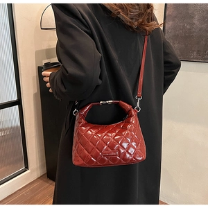 Detail of red quilted patent leather bag with silver hardware on a black blazer