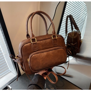 Detail showing retro brown Boston bag with top handles and golden metal buckles