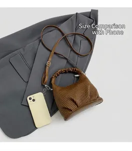Detailed view of brown ruched leather handbag with cloud-shaped handle and silver hardware