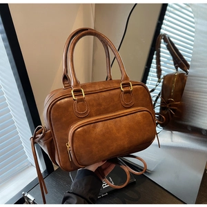 Close-up of vintage brown PU leather handbag featuring brass zippers and textured finish