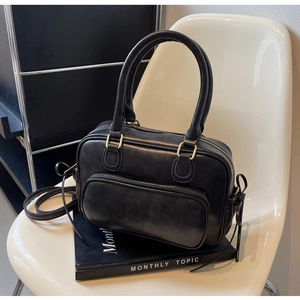 Detail of a vintage black Boston bag featuring matte leather texture and gold hardware