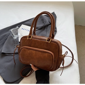 Detail of vintage brown shoulder bag with gold buckles and front zipper pocket on bedding