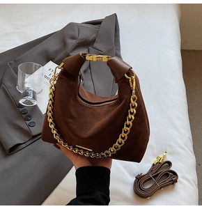 Détail du sac hobo en daim marron foncé avec chaîne dorée et bandoulière amovible