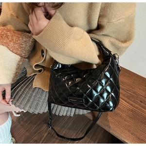 Detailed close-up of quilted black patent leather texture and metallic fashion plaque
