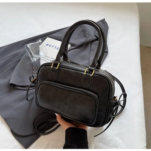 Detail of vintage black matte leather handbag with gold zippers and detachable strap
