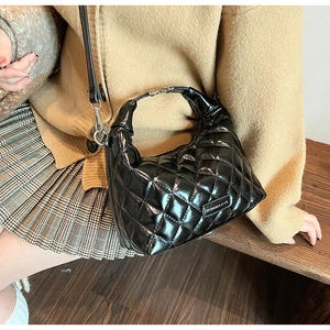 Detail of black quilted patent leather handbag texture and shiny silver hardware accents