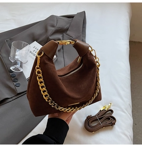 Détail du sac hobo en daim marron foncé avec une grosse chaîne dorée et une anse en cuir