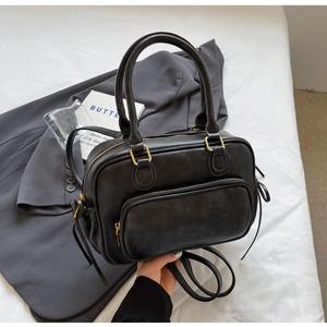 Detail of vintage black matte shoulder bag with gold hardware and front zip pocket