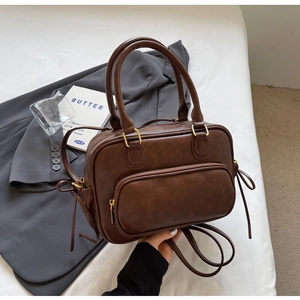 Close-up of vintage brown matte leather handbag with tassel zipper detail and front pocket