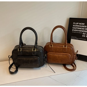 Detail of vintage PU leather bags in black and brown with golden hardware and double handles