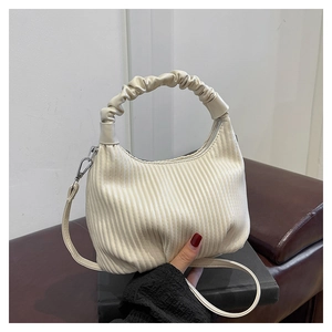 Detail of cream pleated crossbody bag with puffy handle and textured faux leather