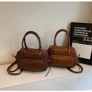 Close-up of vintage brown PU leather bag with dual handles and gold-tone zipper hardware